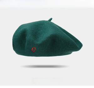 Close-up of dark green wool beret featuring a small red heart embroidery on the side
