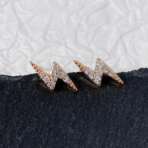 Macro shot of rose gold lightning bolt stud earrings with sparkling cubic zirconia on stone