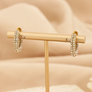 Detailed close-up of C-shaped gold-plated titanium earrings with sparkling crystals
