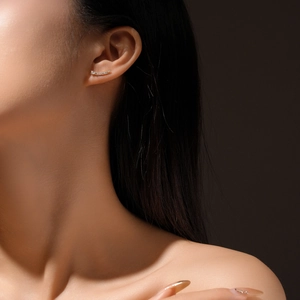 Close-up of s925 silver ear stud with sparkling zircon on model in dramatic lighting