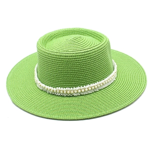 Detail of bright green straw sun hat with delicate white lace trim and pearl accents