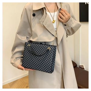 Detail of crossbody tote bag with geometric dots and gold chain strap on trench coat