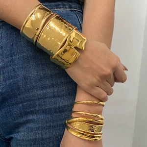 Chunky gold stainless steel open bangles and stacked ring set on denim background