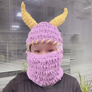 Detail of purple knitted balaclava with yellow devil horns for warm winter headwear
