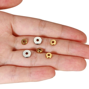 Flache runde Edelstahl-Abstandshalter mit 18k Goldbeschichtung auf einer Handfläche gezeigt