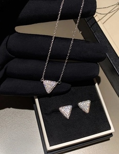 Macro view of silver triangular zircon necklace and earrings set in a black gift box