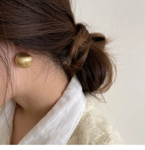 Detail of golden geometric hoop earring with brushed metal finish on model