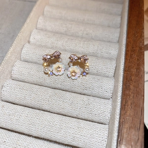 Detailed close-up of bowknot flower earrings with purple crystal hearts and white pearls