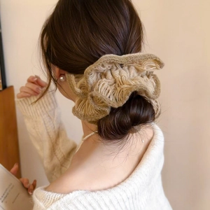 Close-up of knit flower scrunchie detail on a messy bun with elegant texture