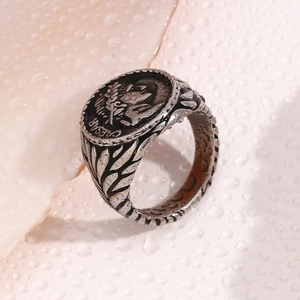 Macro shot of retro silver Caesar coin relief ring on a textured wet surface