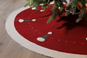 Détail de la jupe de sapin de Noël rouge tricotée avec bordures et motifs de bonnets