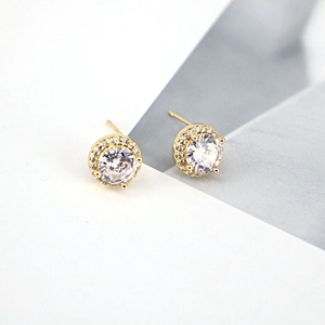 Macro detail of gold halo stud earrings with micro-set cubic zirconia on grey background
