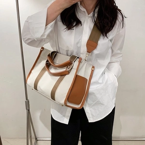 Minimalist canvas tote bag with brown leather handles and adjustable shoulder strap