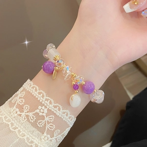 Detail of beaded bracelet with purple jade beads and gold leaf charms on a wrist