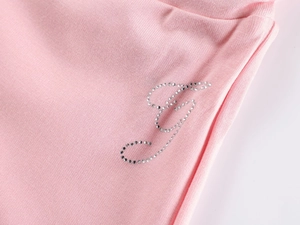 Macro shot of pink knit fabric featuring a sparkling rhinestone letter J decoration