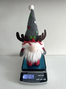 Close-up of a Christmas gnome figurine with reindeer antlers on a scale weighing 101.5g