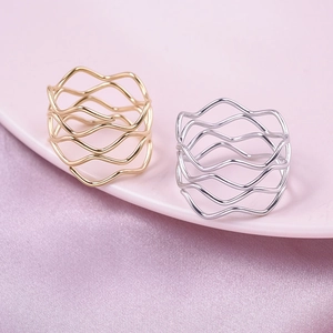 Detailed shot of wave-shaped layered rings in gold and silver finish on velvet