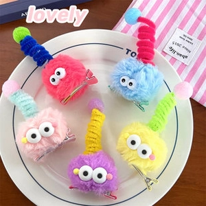 Detalle de pinzas para el pelo de monstruos de peluche de colores con ojos móviles en plato