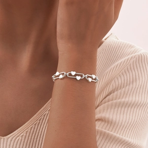 Polished stainless steel link bracelet with solid heart charms on female wrist