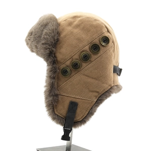 Detail of khaki trapper hat featuring faux fur lining and vintage bronze metal buttons