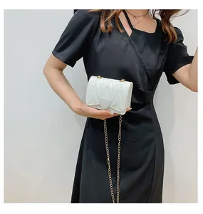Detail of white heart-shaped crossbody bag with V-quilted texture and gold chain strap