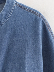 Close-up of the collar stitching and denim texture on a cropped blue jean jacket