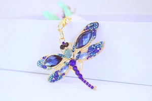 Detailed close-up of dragonfly keychain with blue and purple crystals on gold metal