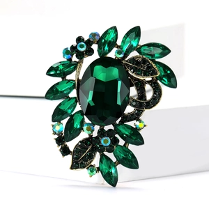 Macro detail of luxury green crystal brooch with golden base on white background