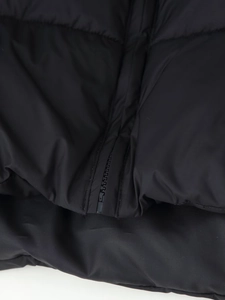 Macro shot of heavy-duty metal zipper and stitching on the black winter coat hem
