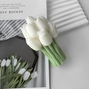Macro view of white tulip bouquet candle with green stems on minimalist background