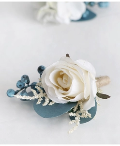 Macro shot of white silk rose boutonniere with blue berries and jute twine detailing