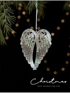 Iridescent crystal angel wing ornament hanging on a Christmas tree branch with bokeh light