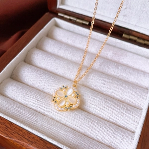 Macro detail of clover necklace with white mother-of-pearl, pearls and blue gemstones