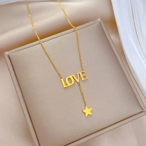 Detailed macro of golden titanium steel LOVE necklace with star pendant on jewelry box
