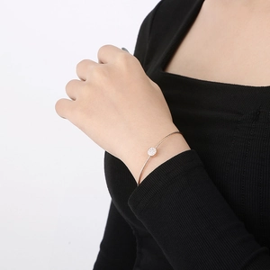 Macro shot of rose gold cable twist bangle with pavé diamond detail on female model's wrist