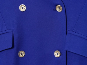 Détails de la veste blazer bleu roi avec boutons dorés en relief et poches à rabat