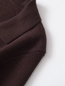 Vue macro détaillée de la texture en maille marron chocolat sur un revers de blazer