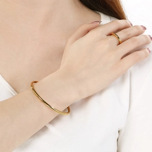 Close-up of minimalist 18k gold-plated 3mm round bangles and rings on a model