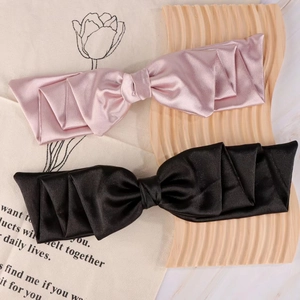 Detail of pink and black satin bow hair clips on a decorative wooden tray