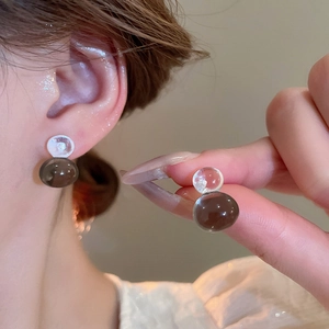 Detailed view of translucent brown and clear resin gourd earrings on model ear