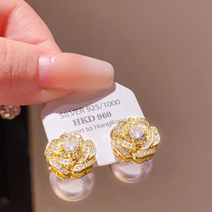Macro shot of 925 silver camellia flower earrings with rhinestones and white pearls