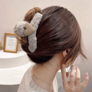 Detail of plush grey shark hair claw clip with a khaki heart on a model hair style