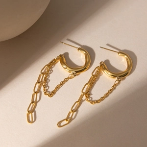Detail of gold-plated tassel earrings with C-shape hoops and hanging chain link fringe
