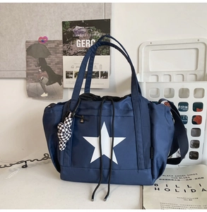 Blue nylon tote bag with white star print featuring drawstring closure and side pockets