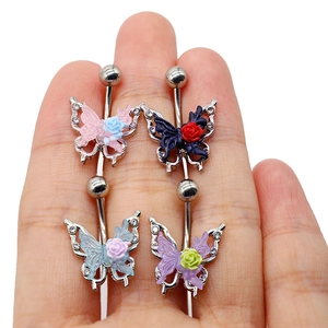 Macro shot of butterfly and rose belly rings held in hand to show size and scale