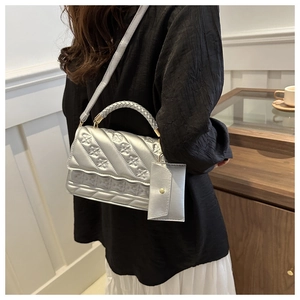 Detailed side view of a silver textured crossbody bag with a small coin purse charm