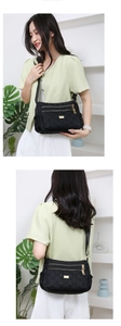 Detail of black quilted oxford cloth shoulder bag with golden zippers and multi-pockets
