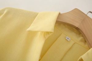 Detail shot of the linen blend fabric texture and collar on a yellow v-neck blouse