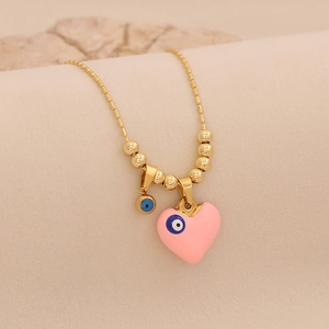 Gros plan d'un collier doré avec pendentif cœur rose et breloques œil bleu
