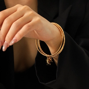 Eleganter 18k vergoldeter dreilagiger Armreif mit Anhänger, präsentiert am Handgelenk
